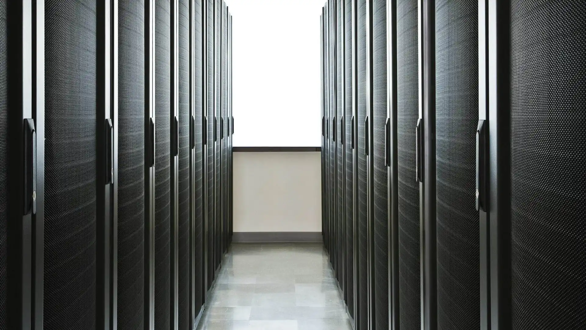 Storage racks aligned in a computer server room with a large window in the background.